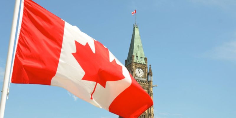 The Canadian flag flapping in front of a clocktower; JackpotCity Casino Blog The Canadian flag flapping in front of a clocktower; JackpotCity Casino Blog