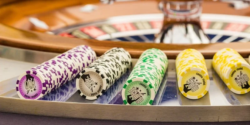 Roulette chips in front of roulette wheel Roulette chips in front of roulette wheel