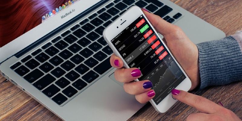 Woman trading stocks on a smartphone app Woman trading stocks on a smartphone app